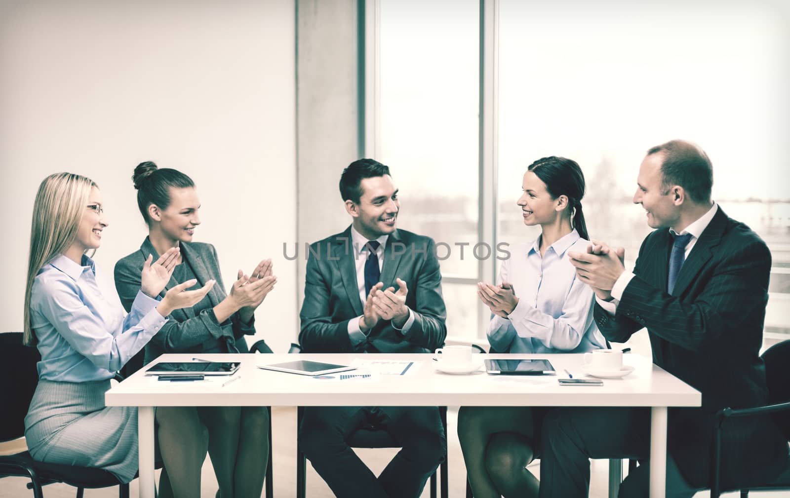 business, technology and office concept - happy business team with laptop computers, documents and coffee clapping hand