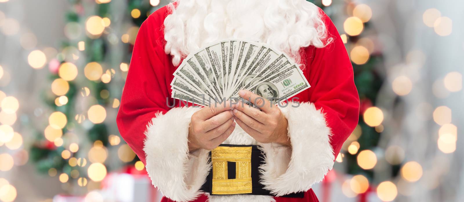 christmas, holidays, winning, currency and people concept - close up of santa claus with dollar money over tree lights background