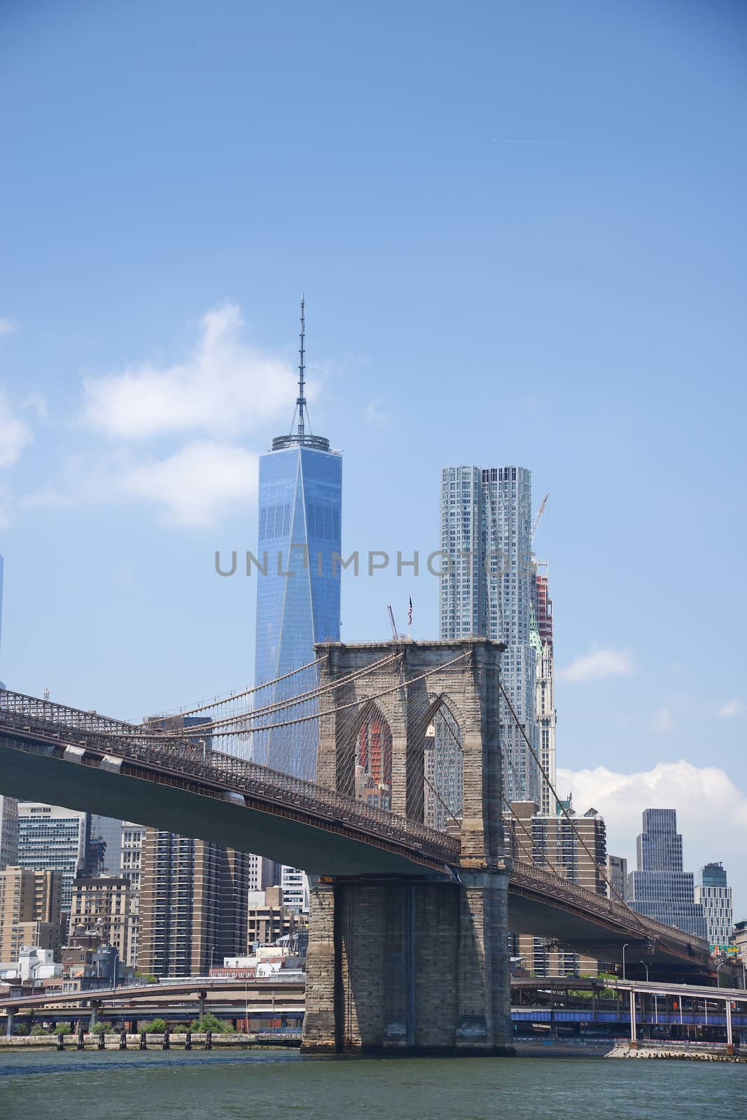 brooklyn bridge under a blue sky with downtown new york city as a background