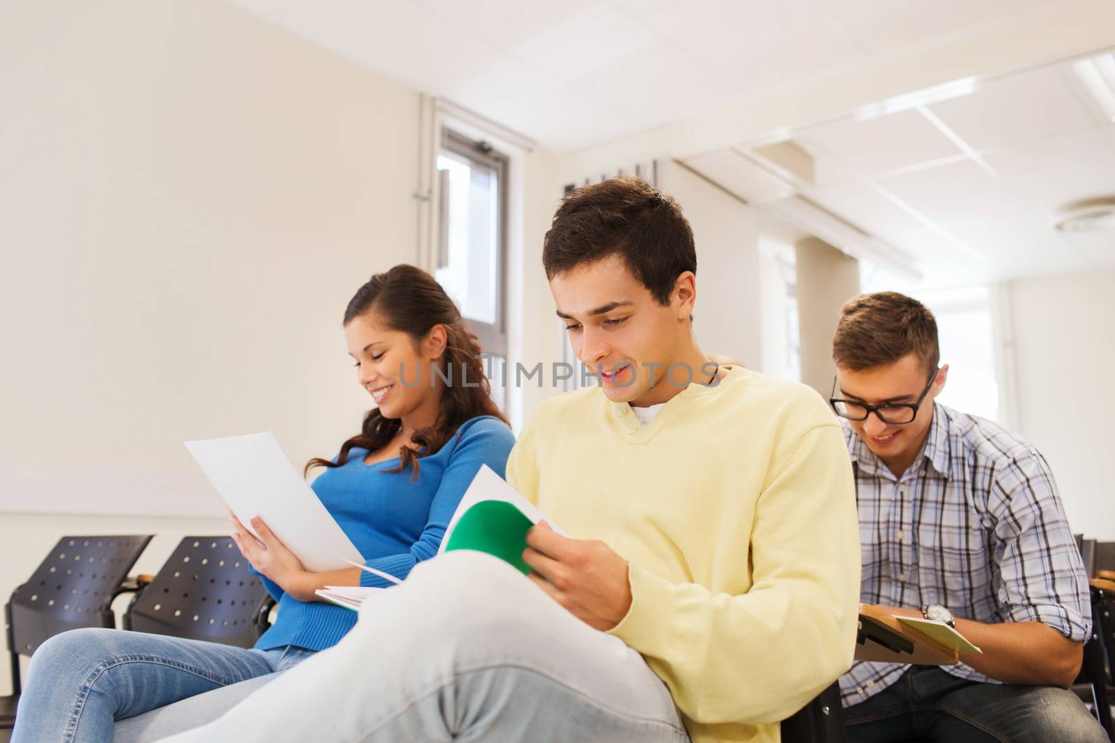 education, high school, teamwork and people concept - group of smiling students with notepads sitting in lecture hall