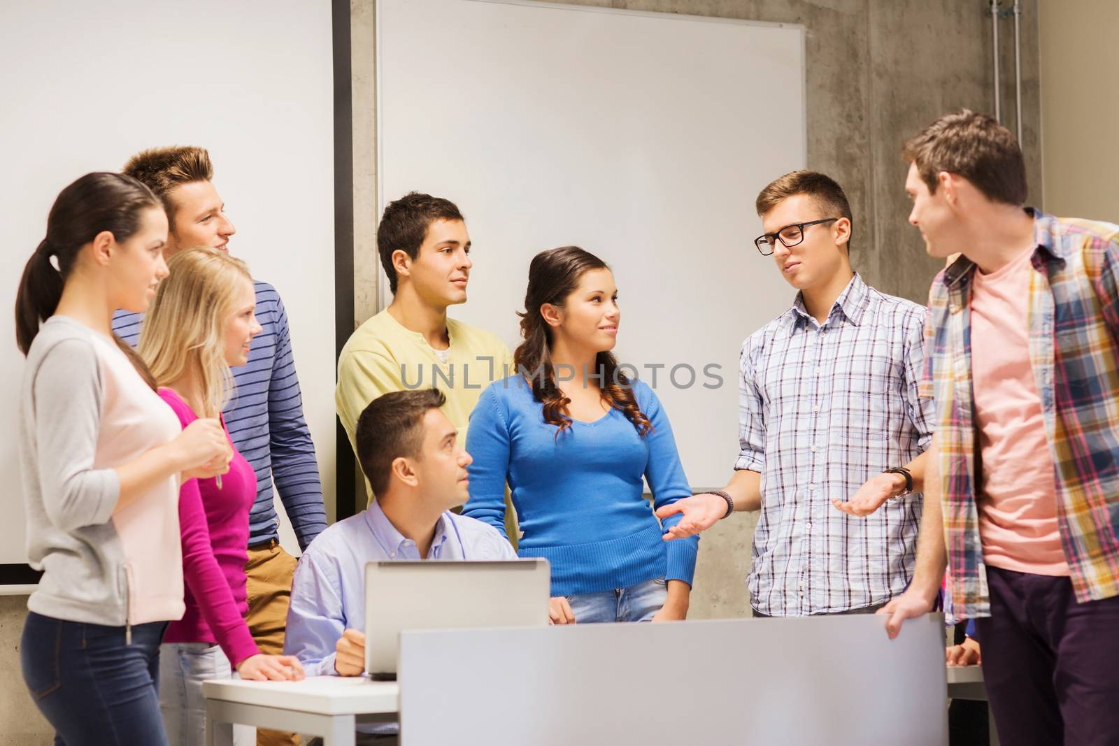 education, high school, technology and people concept - group of smiling students and teacher with laptop computer in classroom