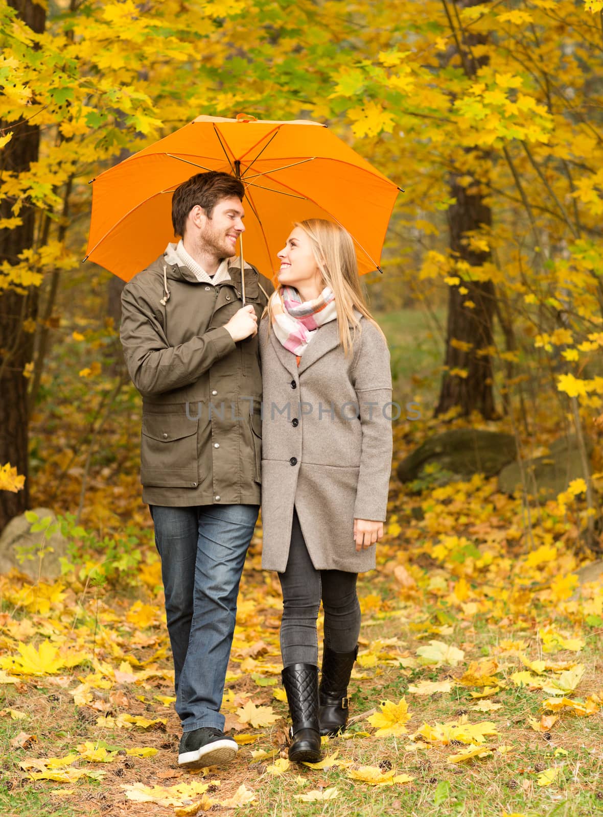 love, relationship, season, family and people concept - smiling couple with umbrella walking in autumn park