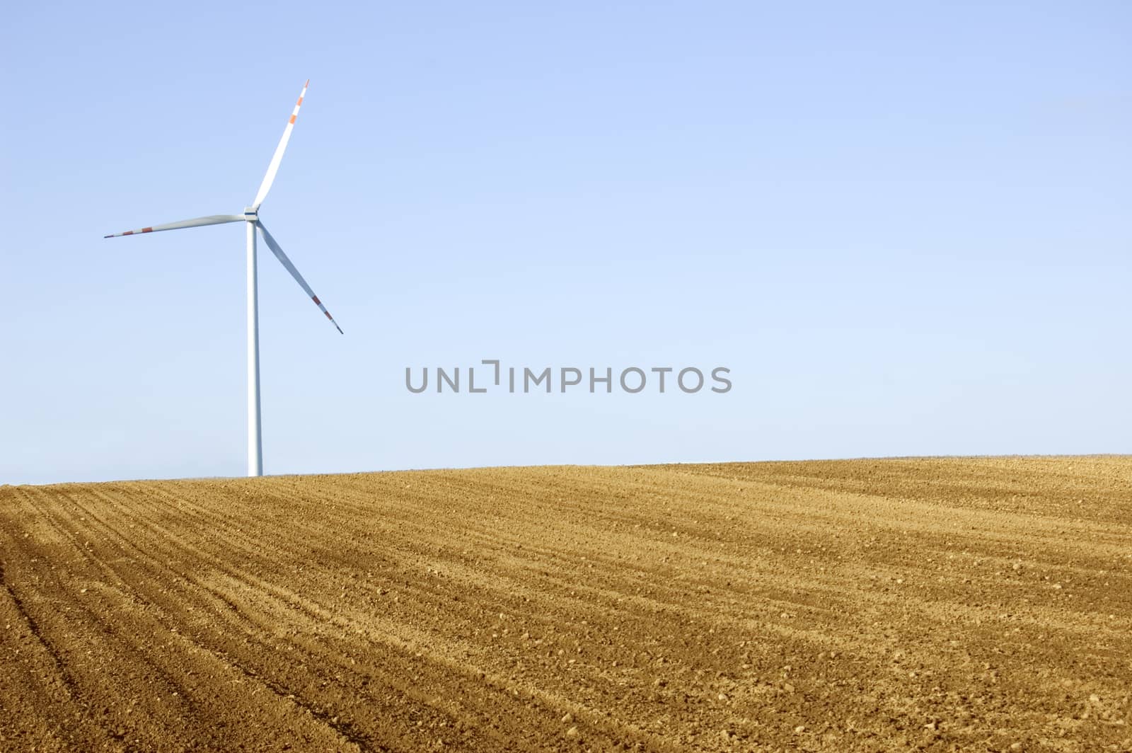 Windmill conceptual image. Windmill on the plowed field.