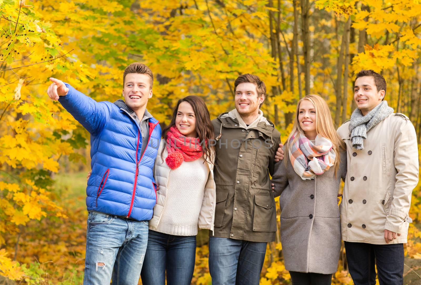 group of smiling men and women in autumn park by dolgachov