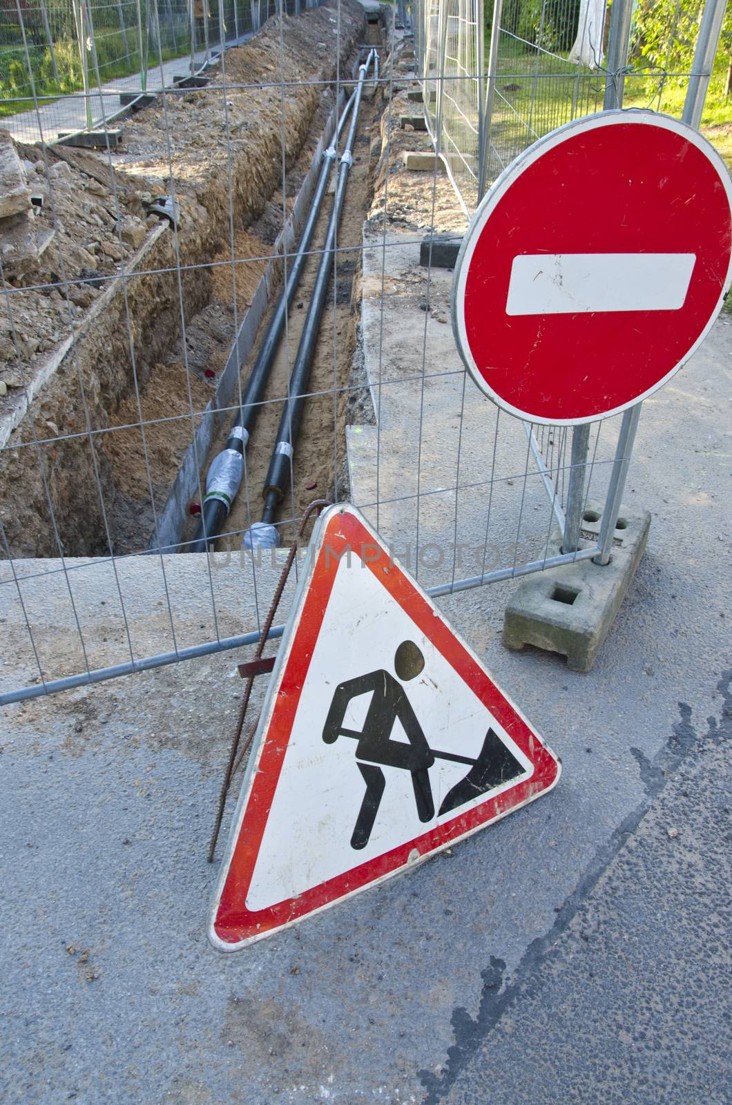 new heating system pipes in trench and road signs on street