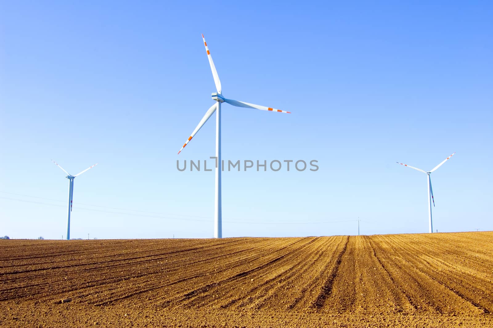 Windmill conceptual image. Windmills on the plowed field.