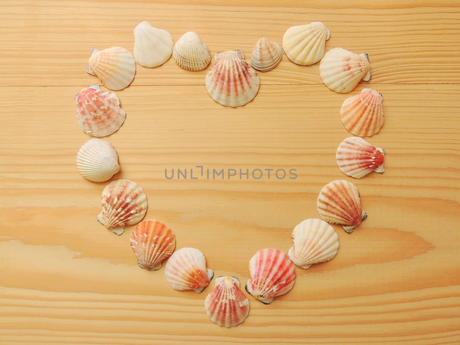 Heart of seashells on a wooden background.
