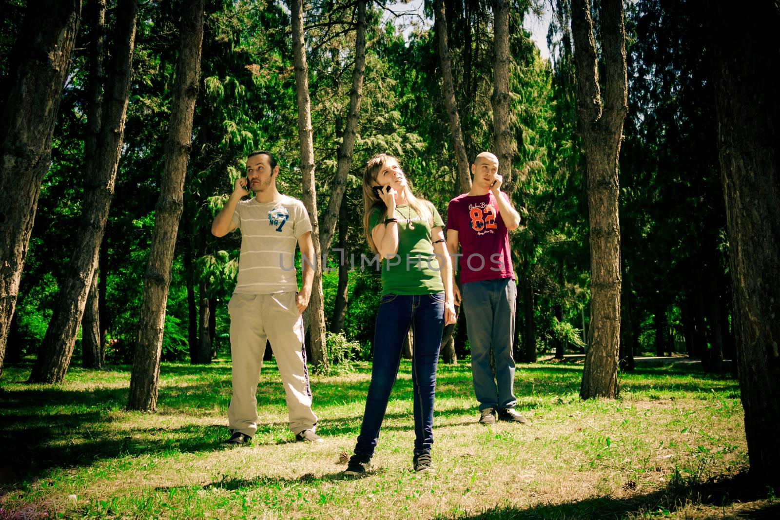 three teenagers talking to the phone in the forest