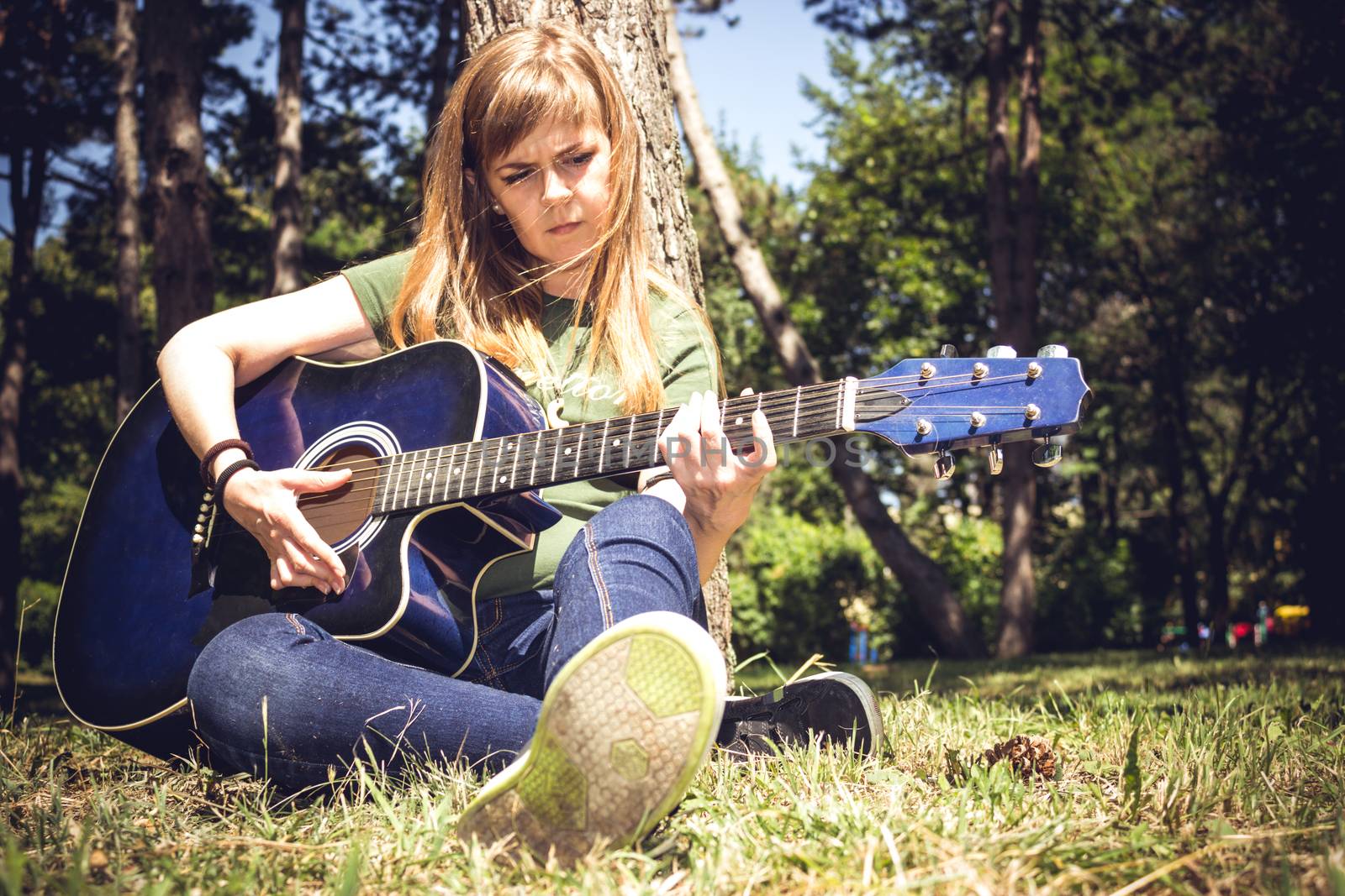 Girl singing to a guitar surrounded by trees in a park