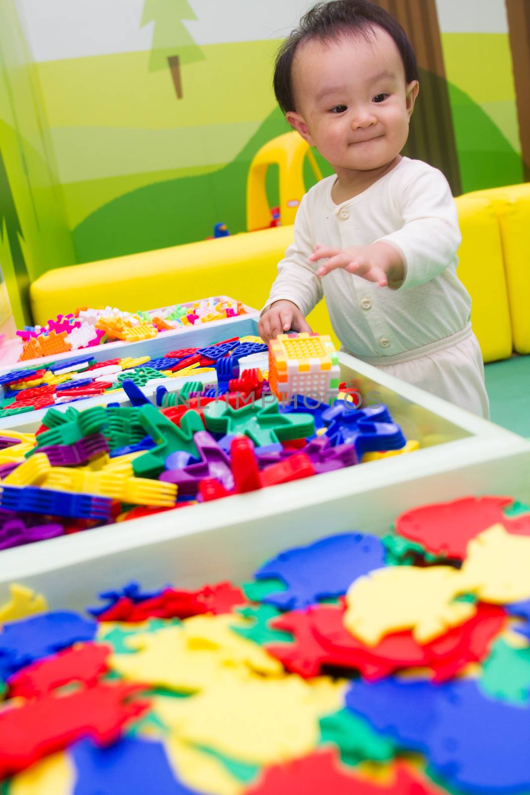 An Asian Chinese baby playing puzzle at indoor playground.