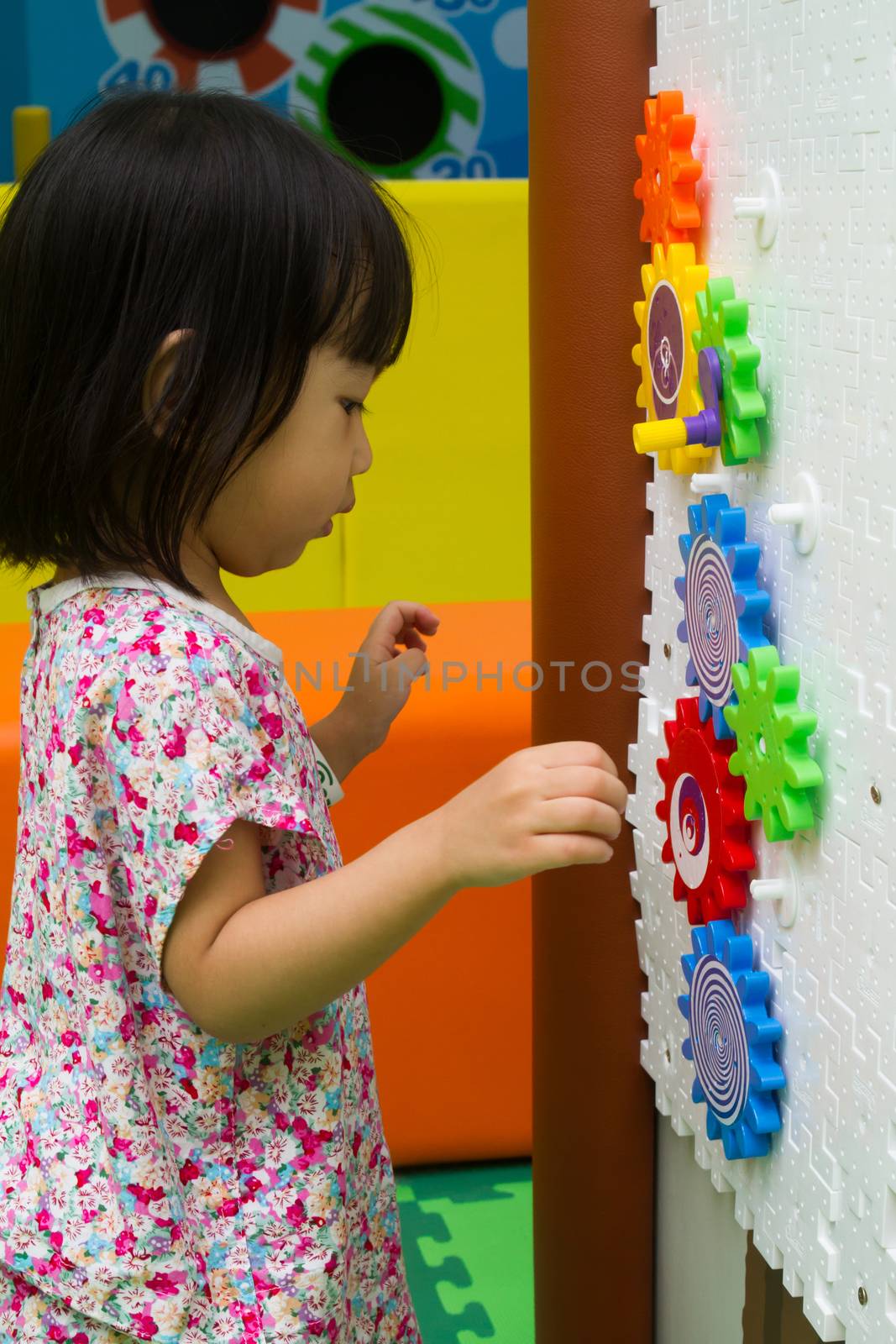 An Asian Chinese girl solving puzzle at indoor playground.