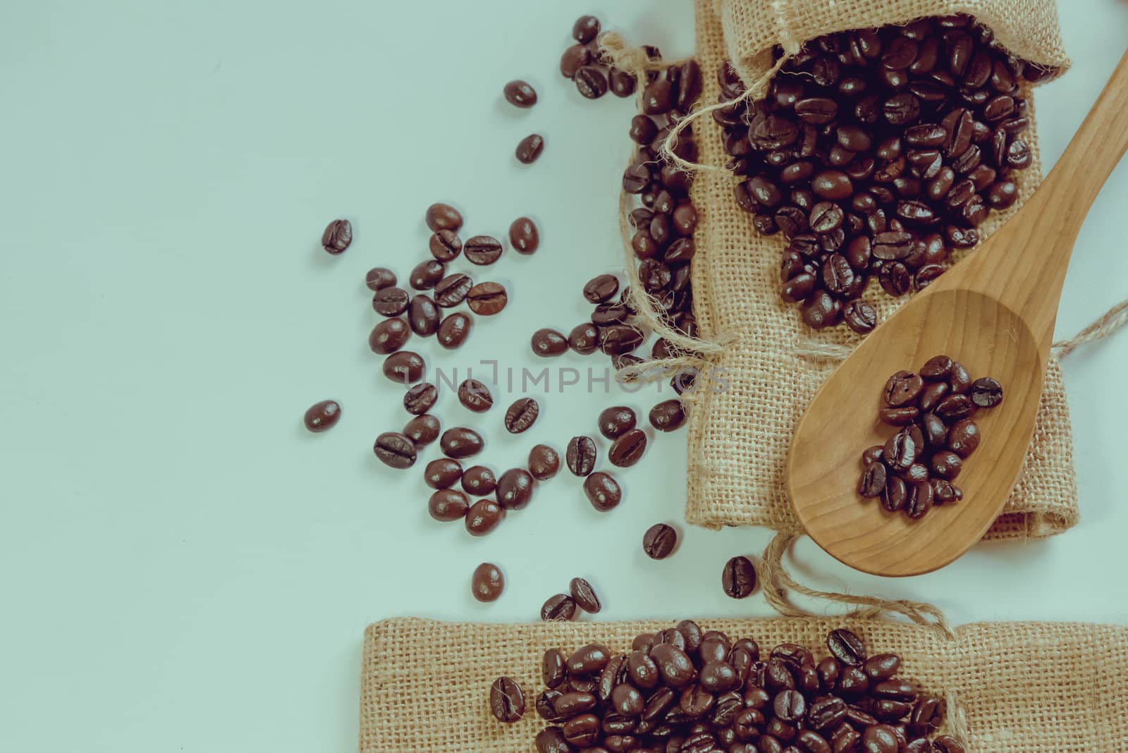 Coffee beans and wooden spoon on sack surface.Filter effect retro vintage style