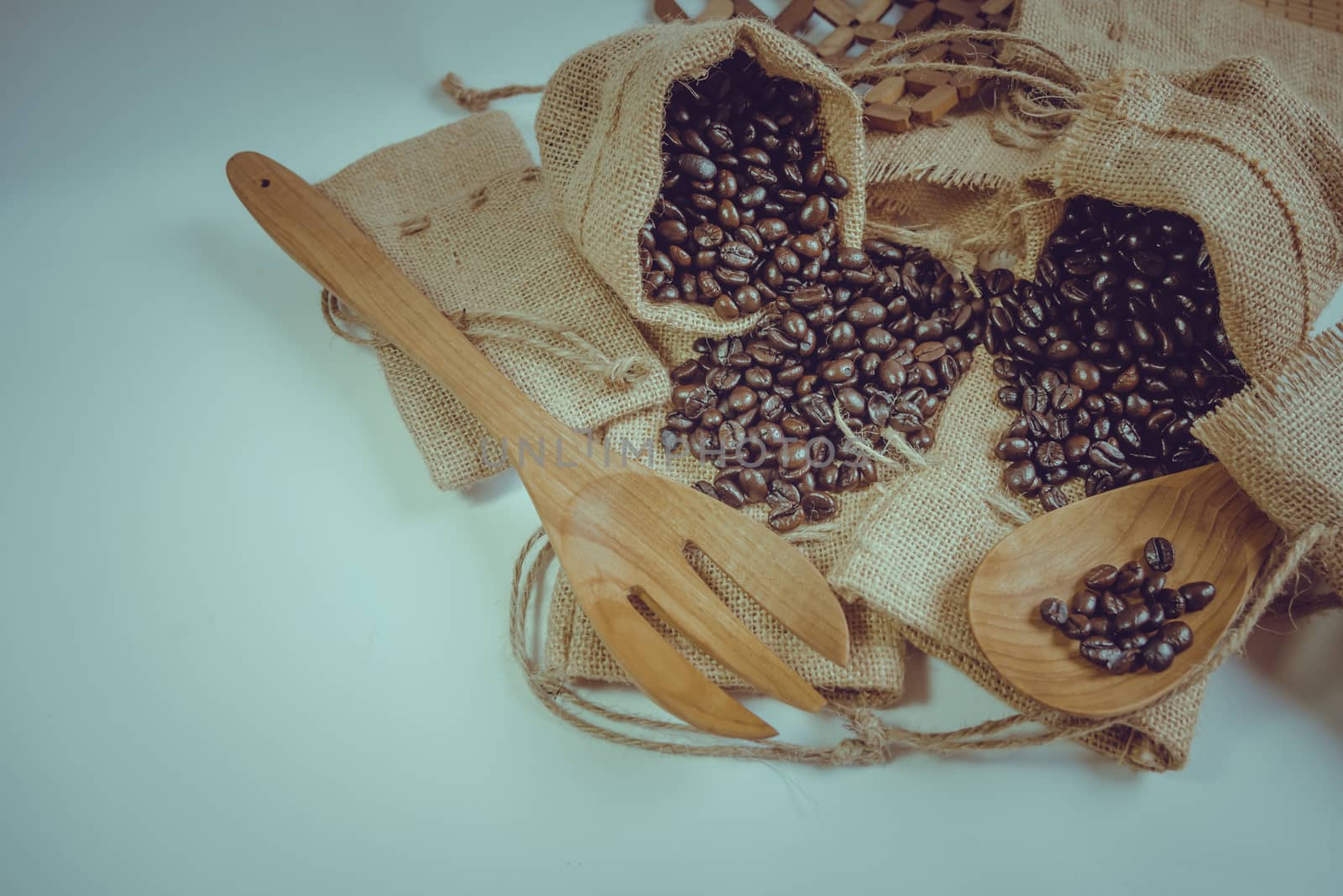 Coffee beans wooden spoon and fork on sack surface.Filter effect retro vintage style