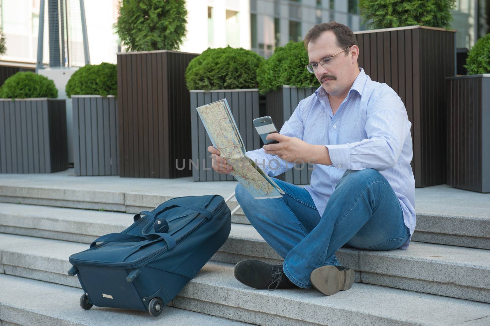 Trendy adult man in the town with touristic map outdoors.