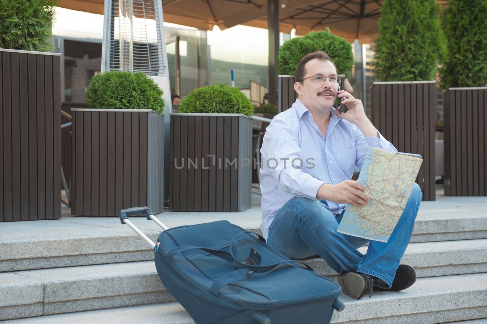 Trendy adult man in the town with touristic map outdoors.