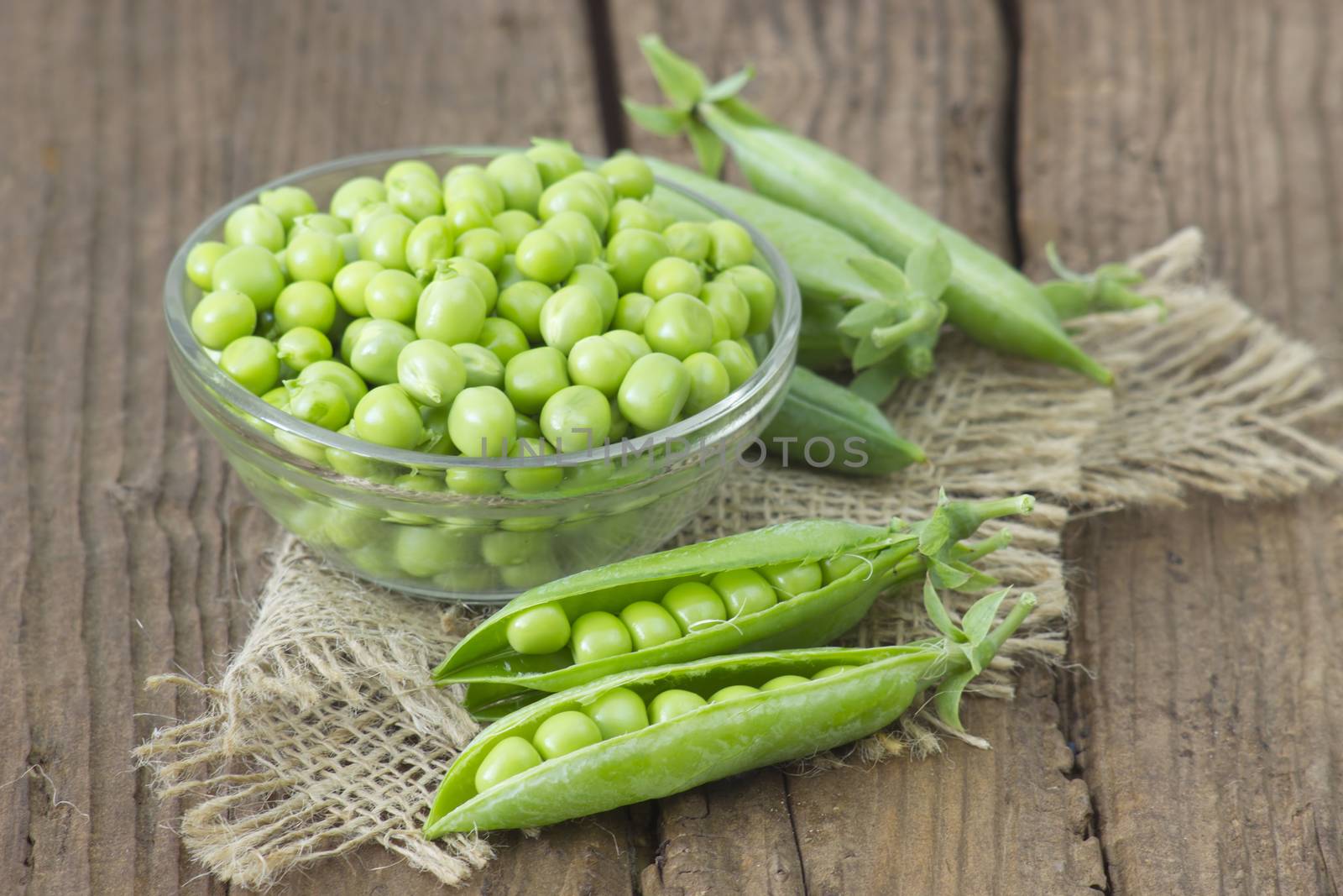 a bowl full of green peas on wooden background by miradrozdowski