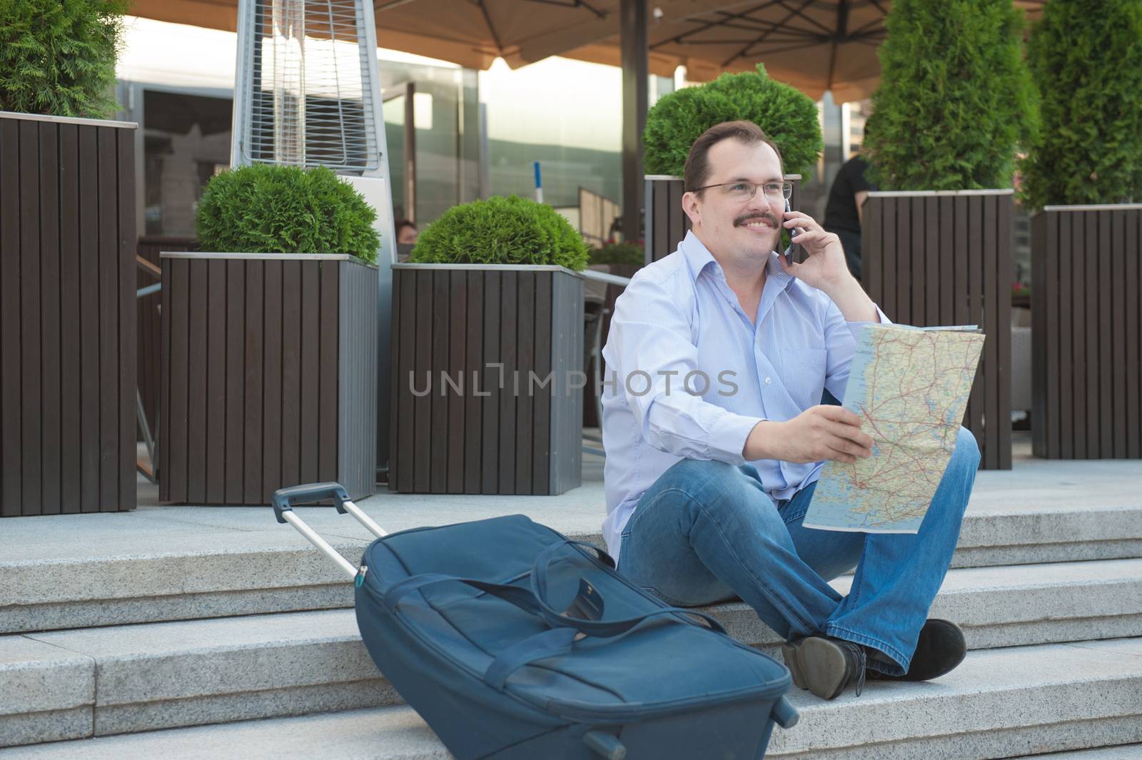 Trendy adult man in the town with touristic map outdoors.