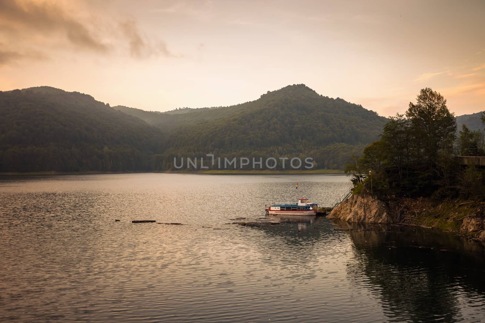 Small boat on the artificial lake behind the Bicaz Dam, at sunset, Romania