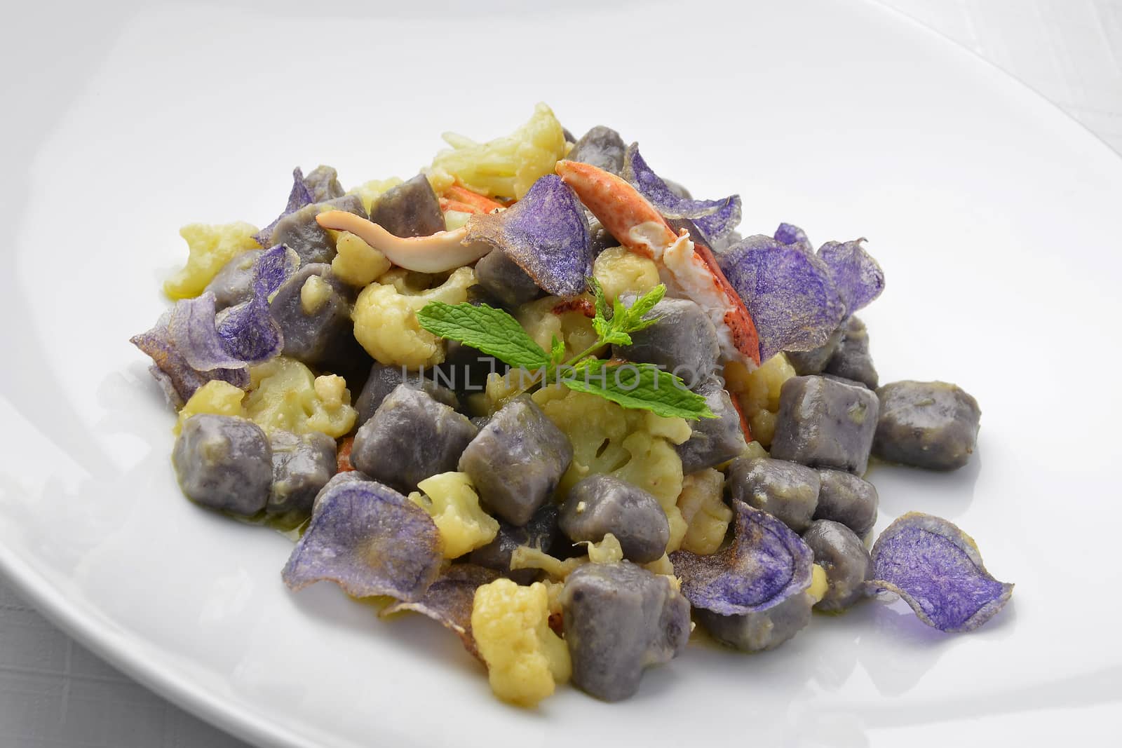 Dish of Purple Potato Dumpligs with  Cauliflower and Lobster in white plate