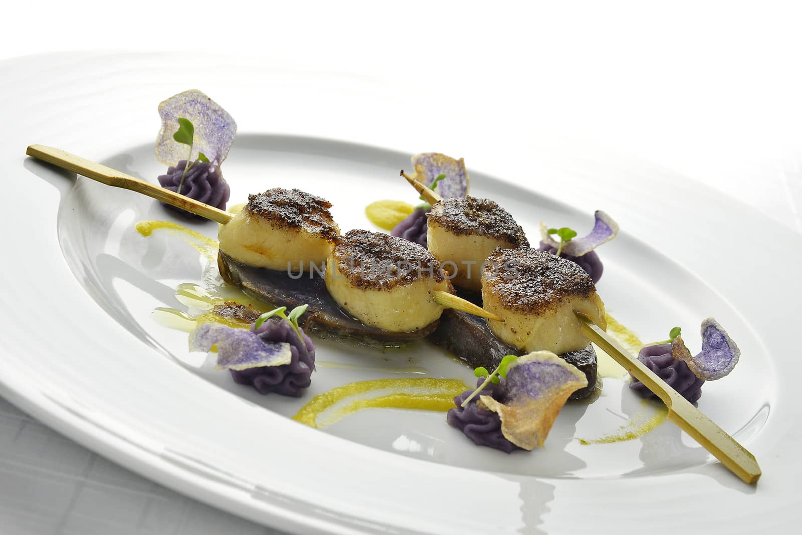 Fish Dish Skewer of Scallops Crusted with black Rice and Purple Potatoes in white plate