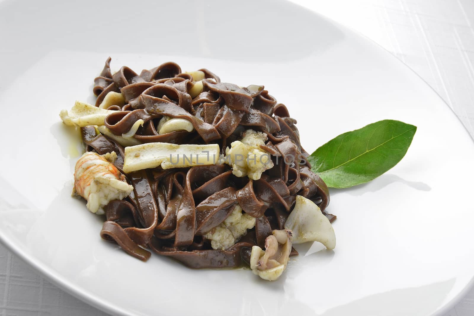 Pasta Dish Chocolate Fettuccine with Prawns and Cuttlefish in white plate