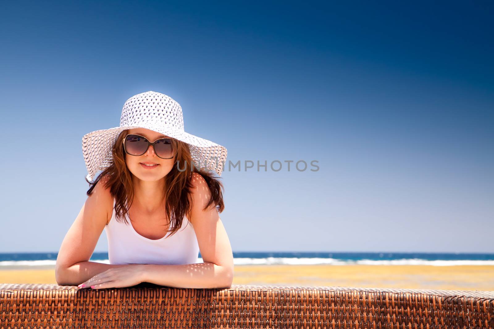 The young beautiful girl in a hat on vacation, on a sunny beach