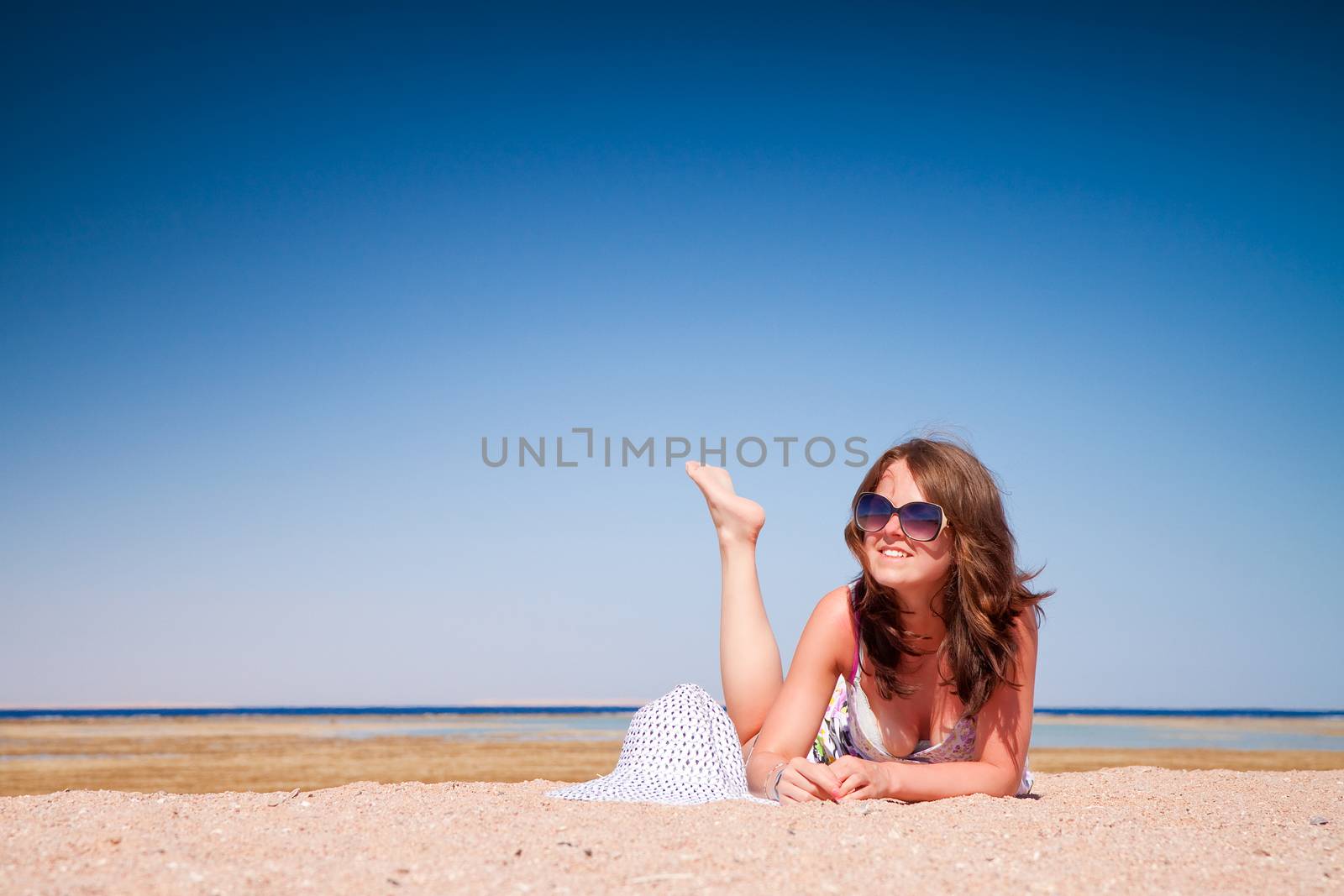 The young beautiful girl in a sunglasses on vacation, on a sunny beach