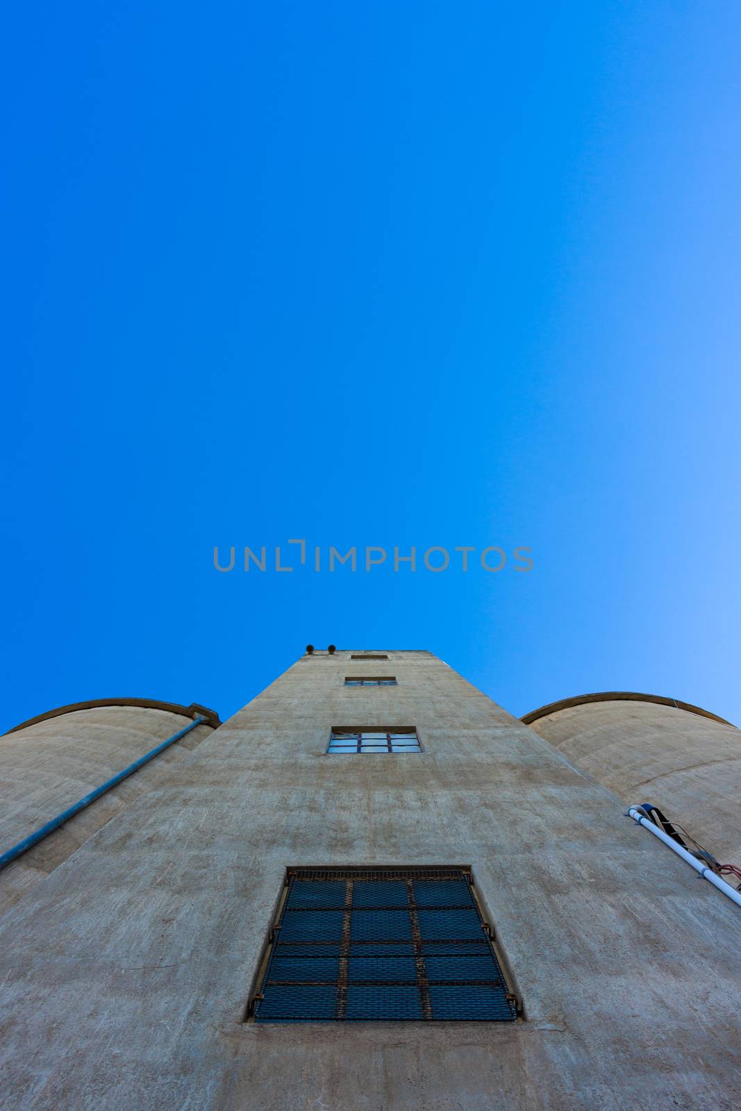 Looking up towards the top of a large silo against blue sky.