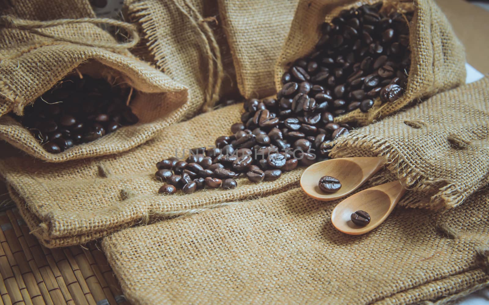 Vintage photo of Coffee beans and wooden spoon on sack surface.