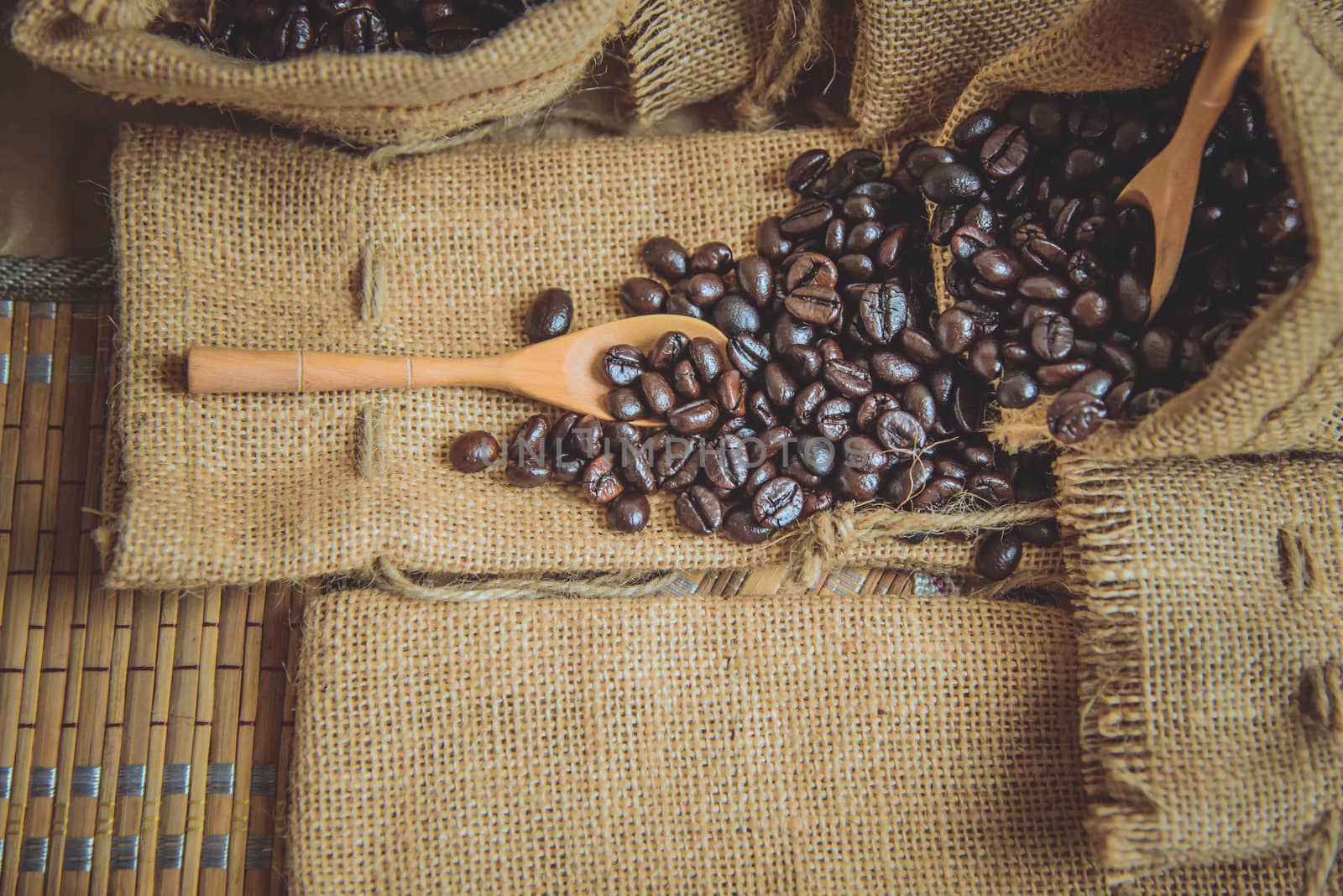 Vintage photo of Coffee beans and wooden spoon on sack surface.