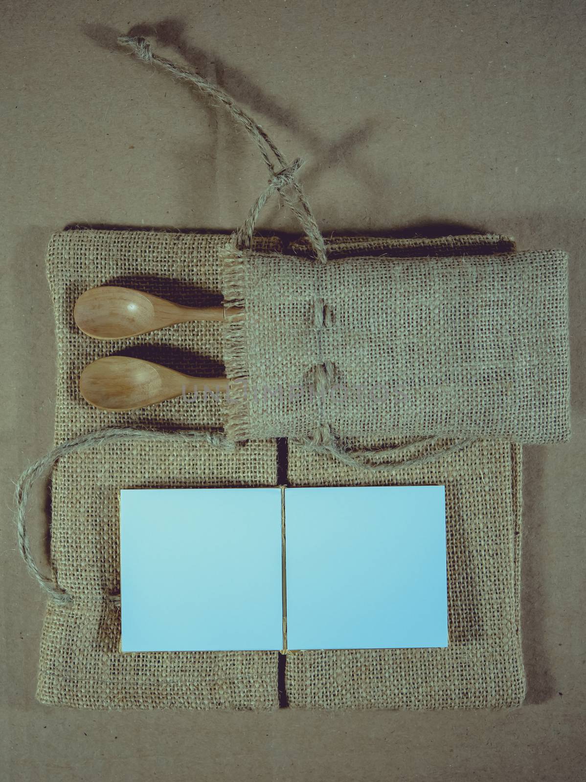 Notepad and wooden spoon on sack surface background.