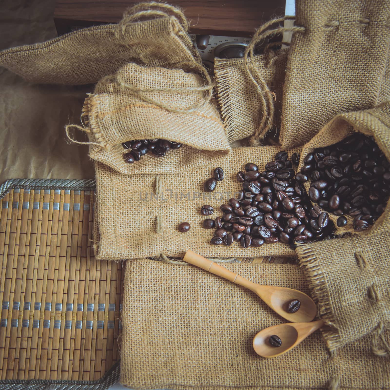 Vintage photo of Coffee beans and wooden spoon on sack surface.