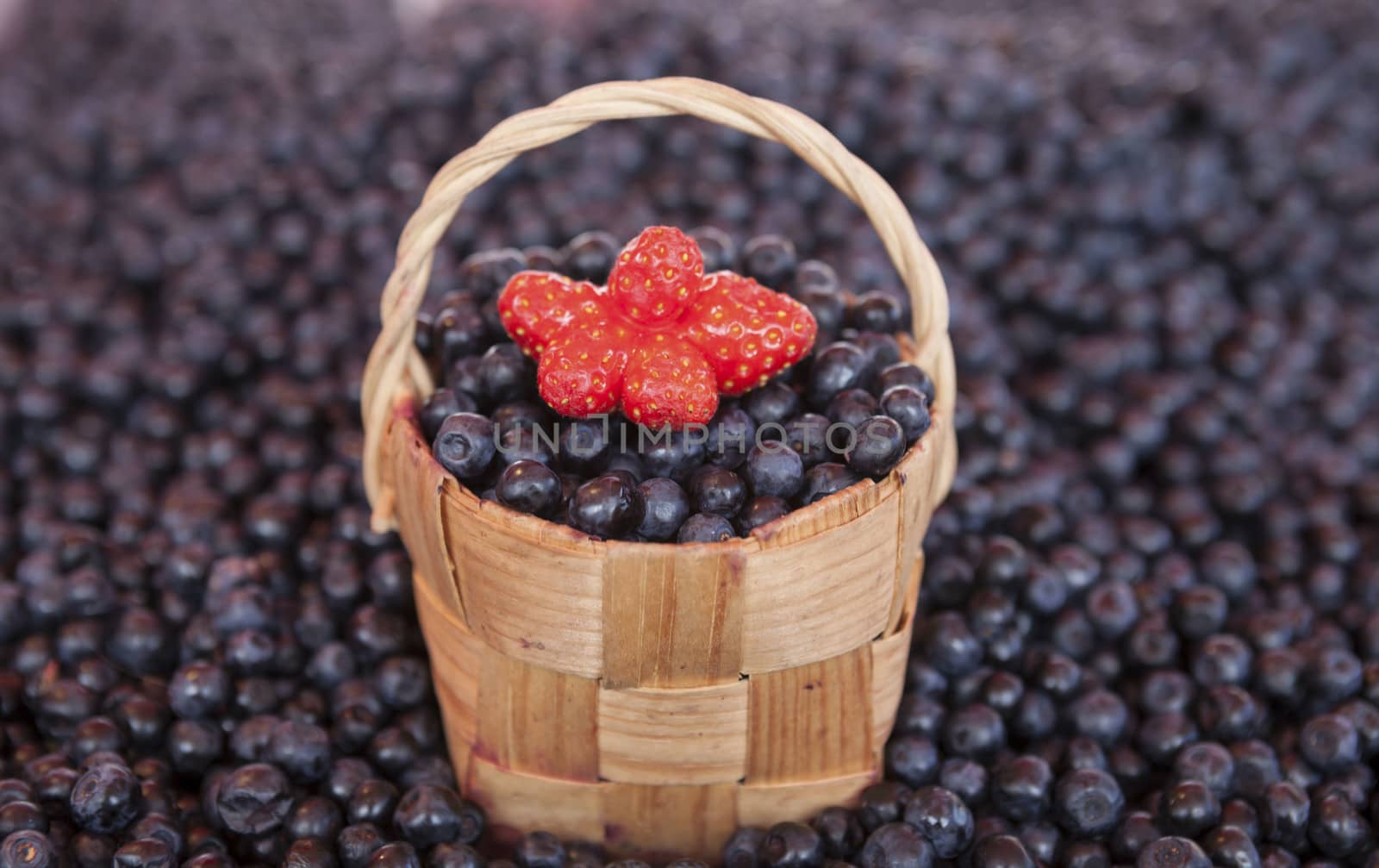 Fresh blueberries with a little basket of strawberries on the market by mcherevan