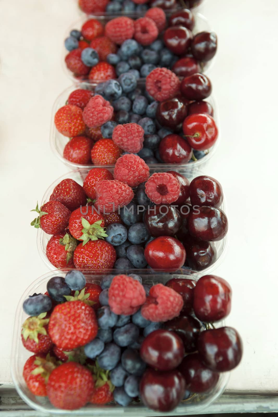 Fresh  raspberries strawberries cherries blueberries in the box on the market.