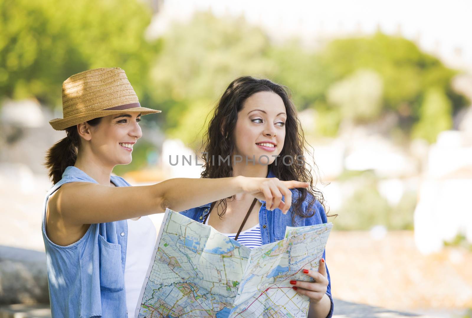 Two beautiful female friends searching a place on the map