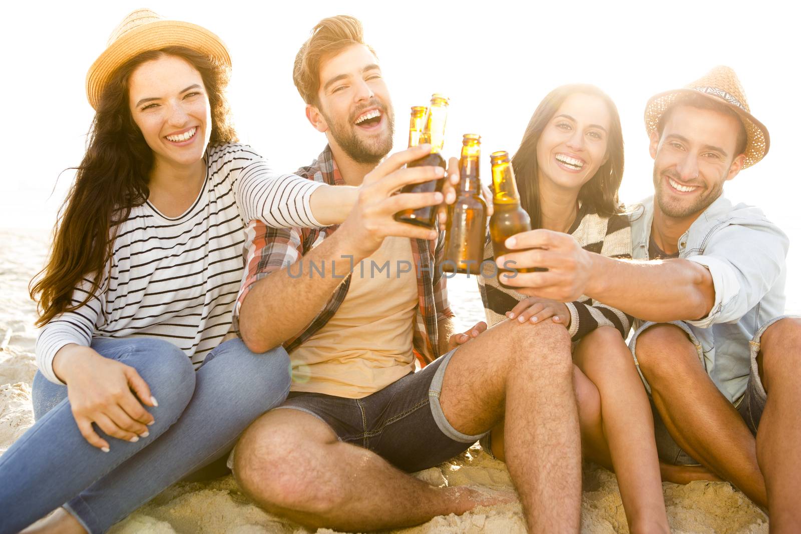 Friends having fun together at the beach and drinking a cold beer