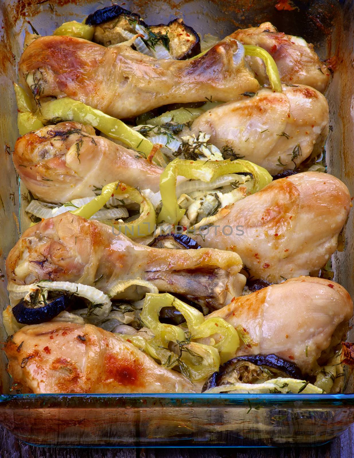 Delicious Roasted Chicken Legs with Green Bell Pepper, Leek and Eggplants in Glass Casserole closeup