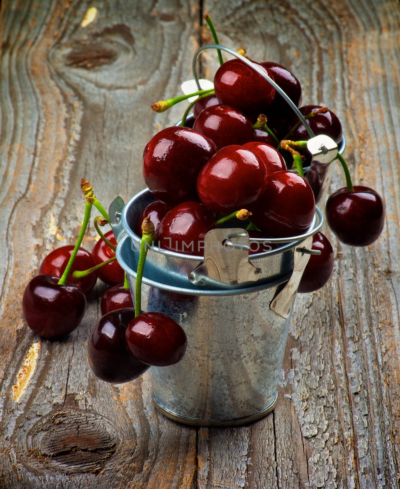 Sweet Dark Red Cherries in Full of Tin Buckets closeup on Rustic Wooden background