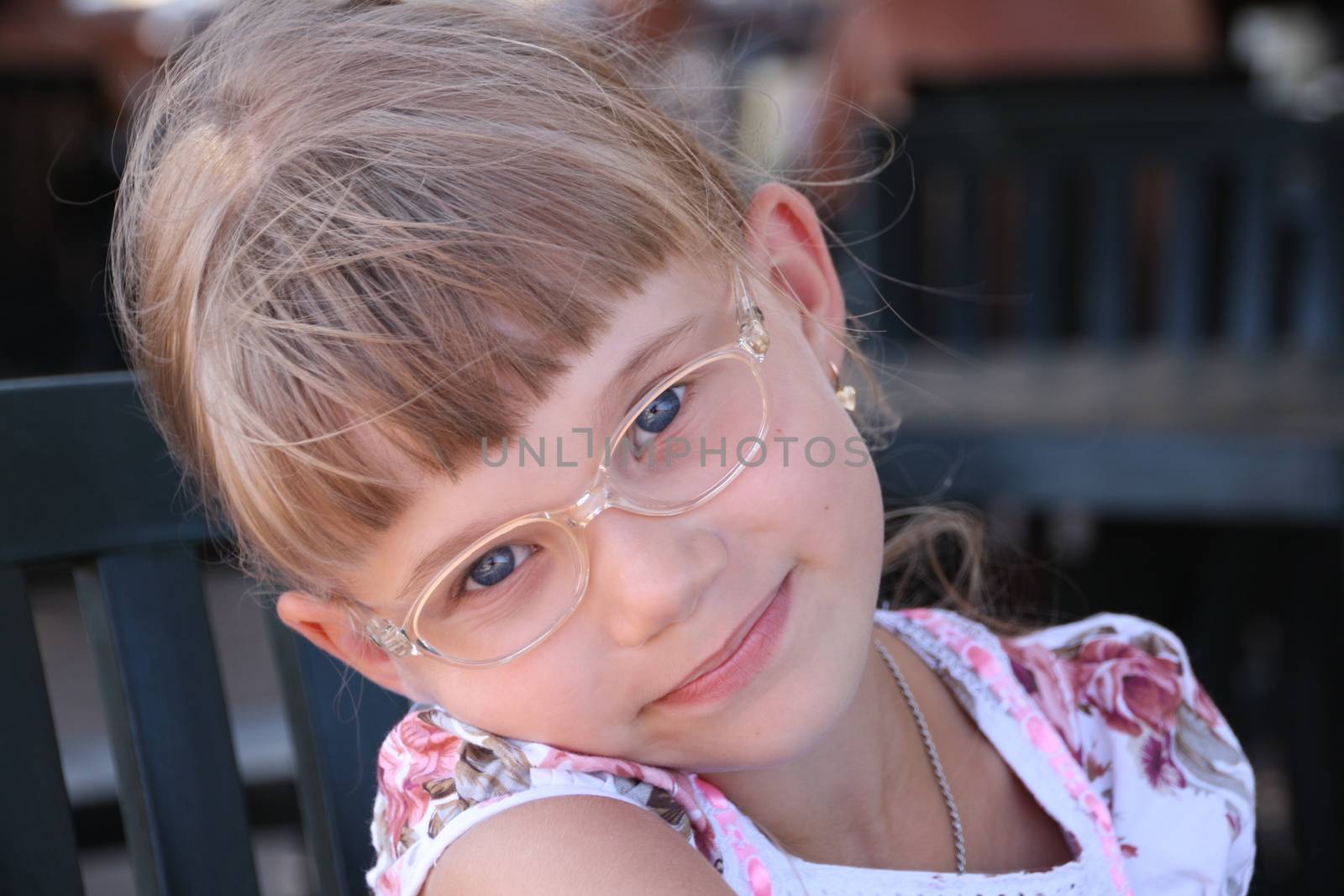 Smiling little blond girl with glasses bent her head