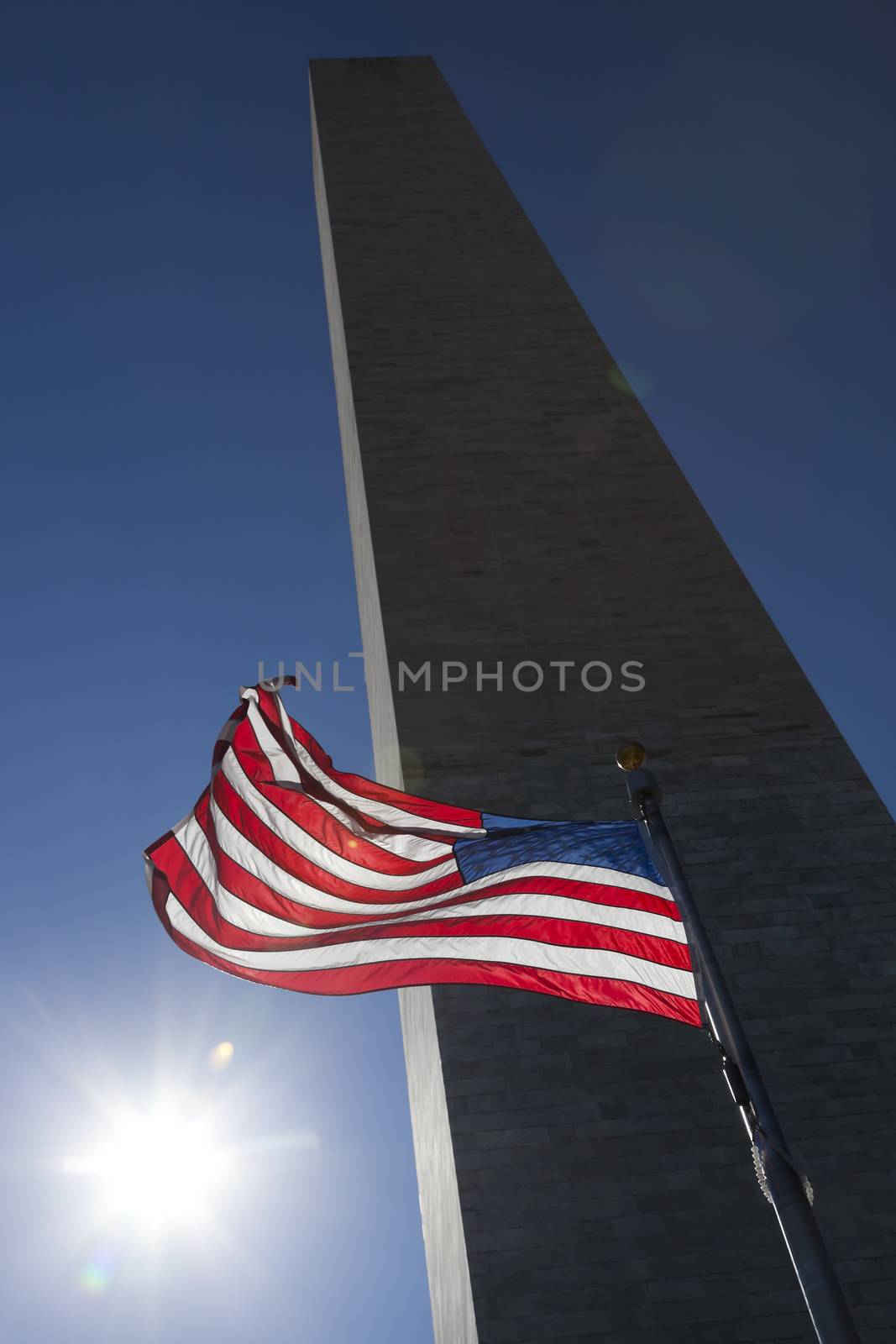 USA flag in the wind dark sky, the sun and Washington Monument