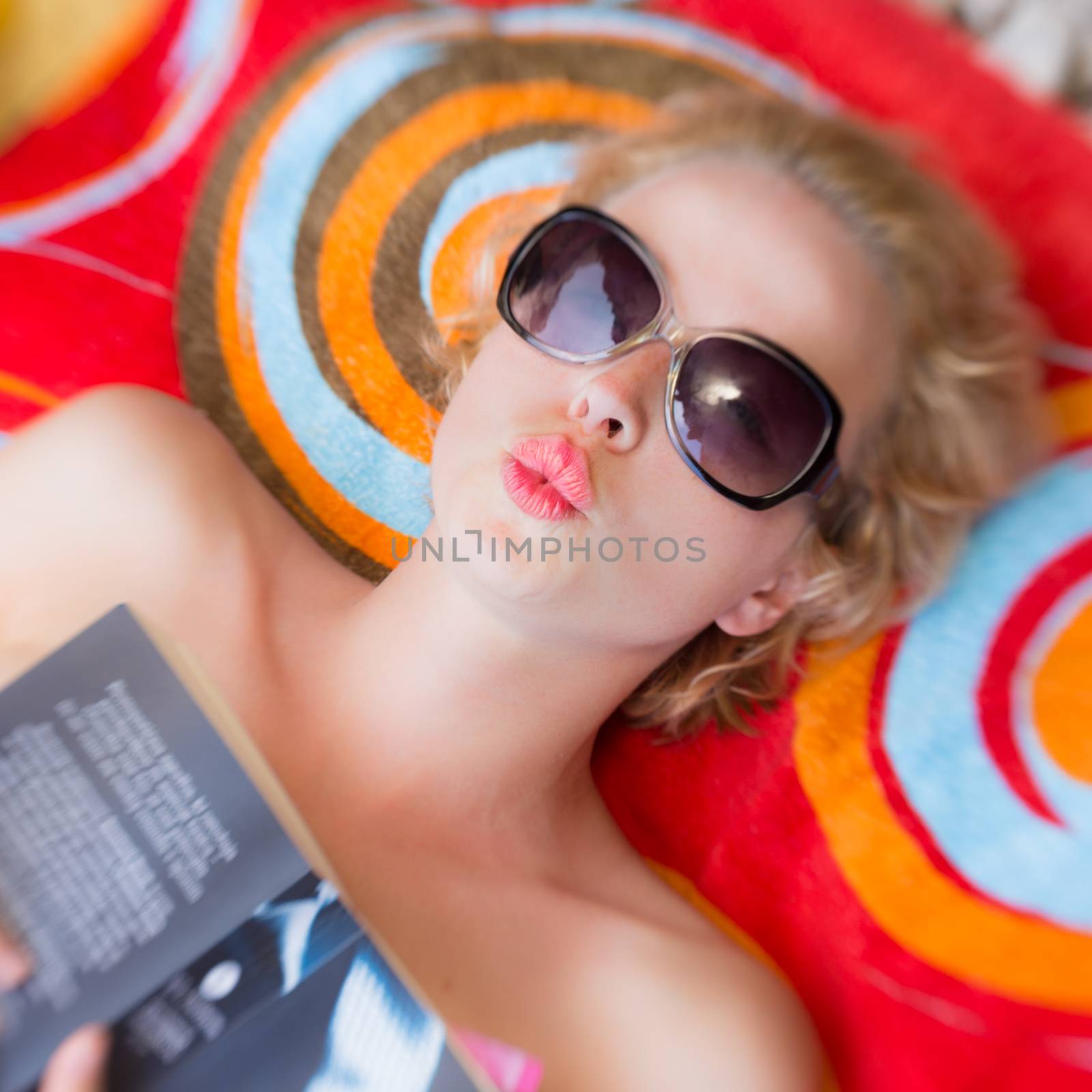Lady reading a book an a beach sending a kiss of summer from vacations.