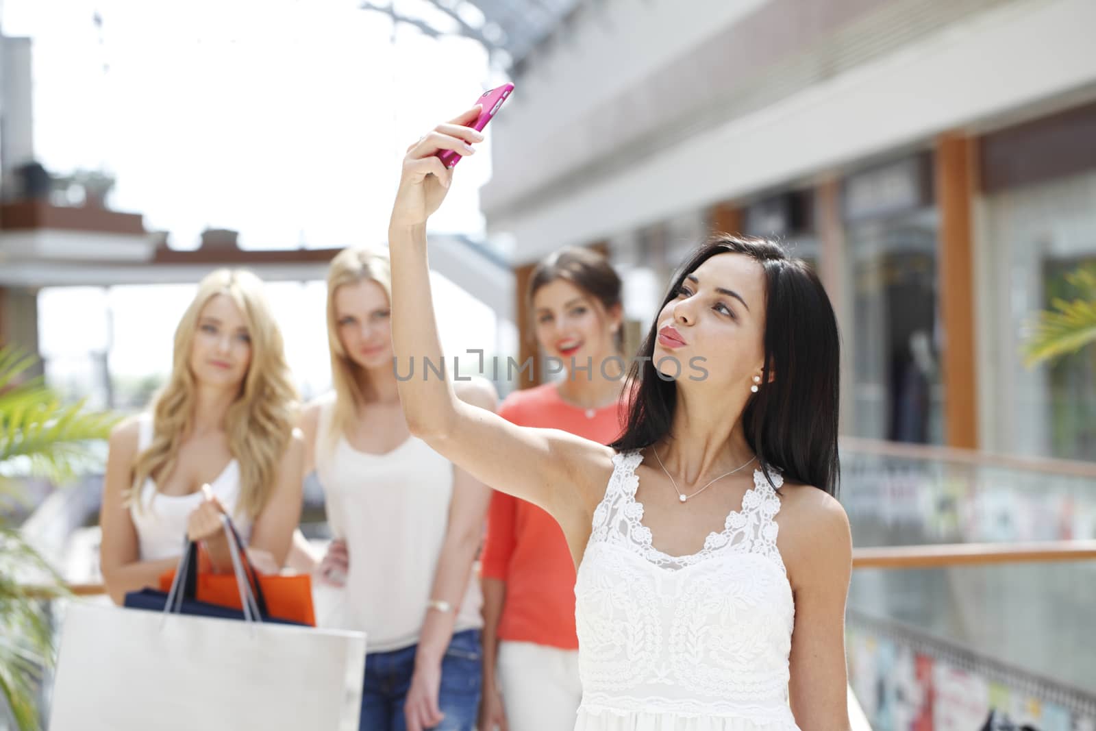 Happy woman with bags taking selfie in shopping mall