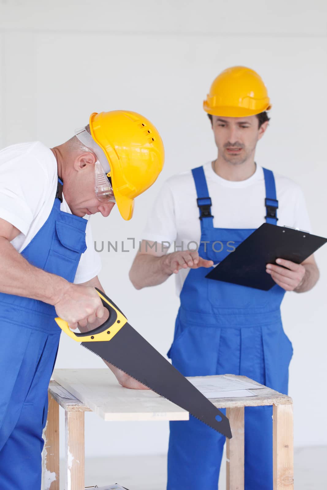 two workmen sawing wooden board
