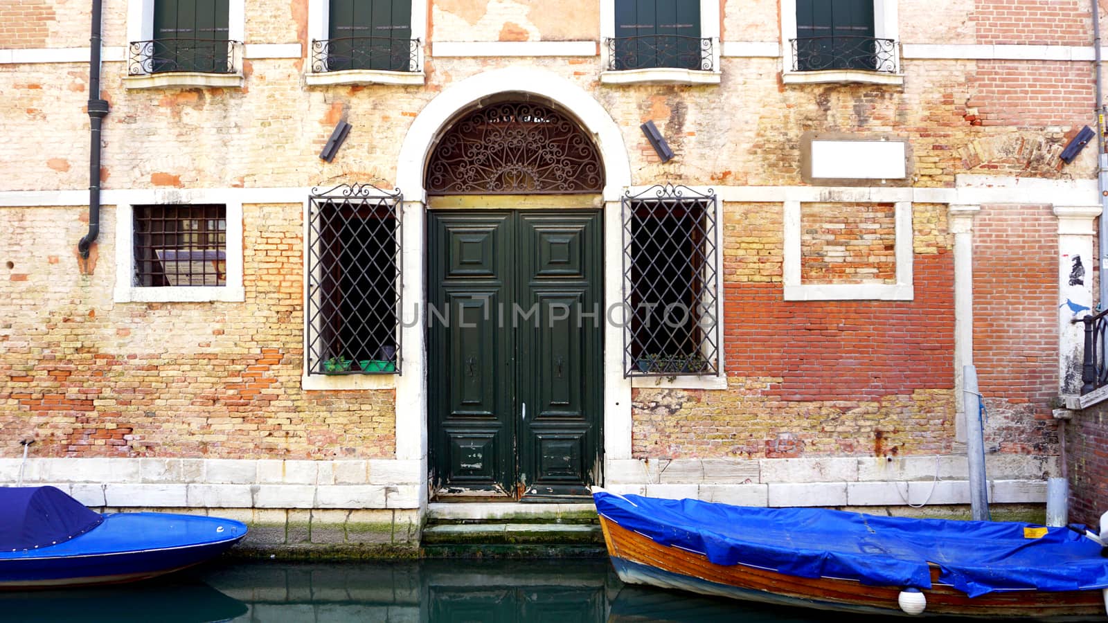 canal and boats with ancient brick wall house elements in Venice, Italy