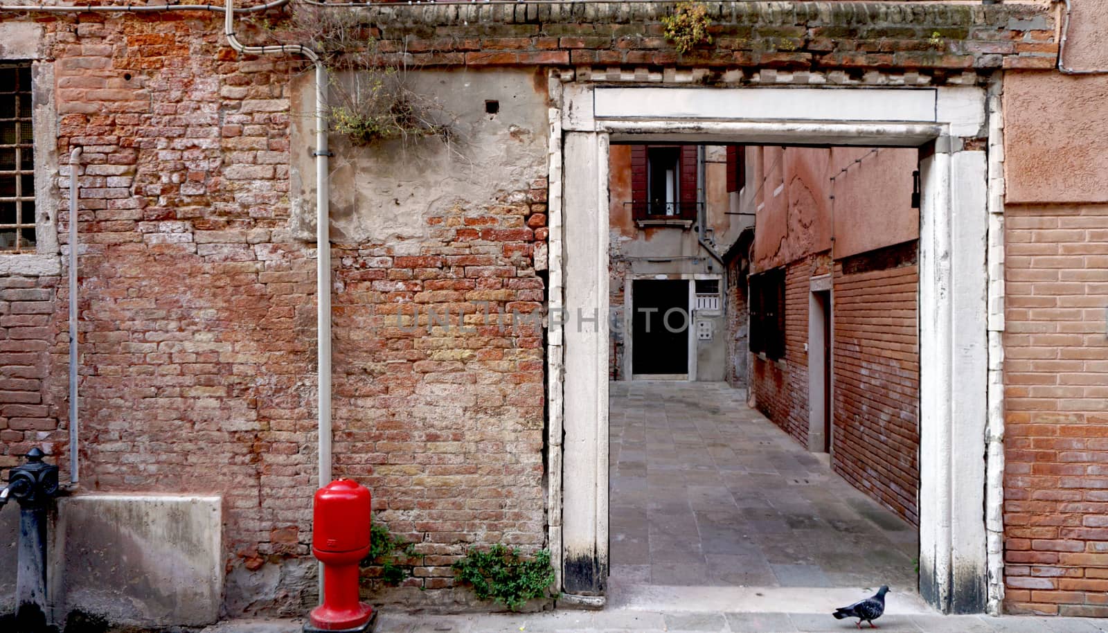 Alley with ancient brick wall building in Venice, Italy
