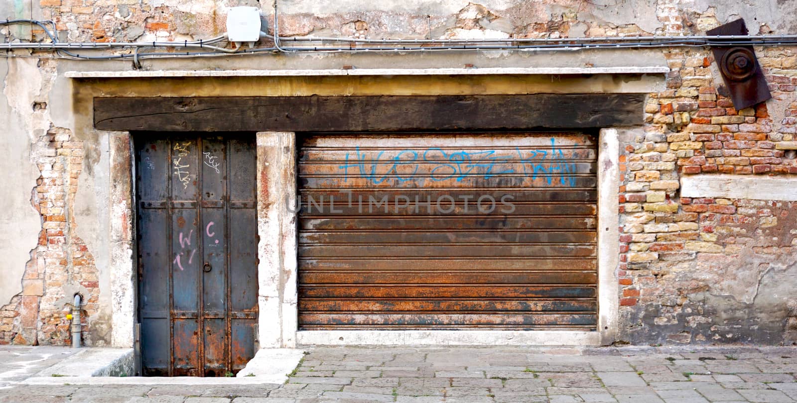 old and rustic metal doors with decay brick wall building in Venice, Italy