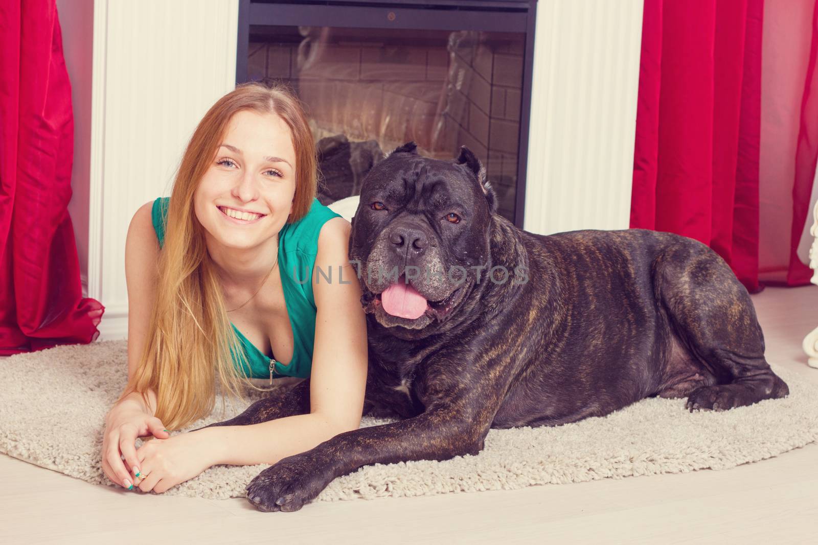 girl is at home next to the fireplace with his big dog Cane Corso by victosha