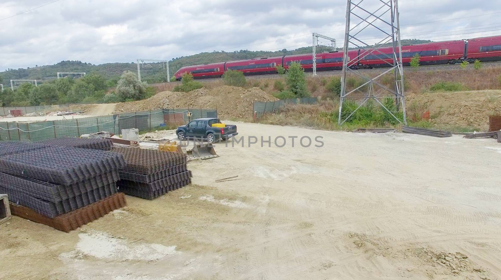 Fast moving train speeding up near a building site. Industrial environment.