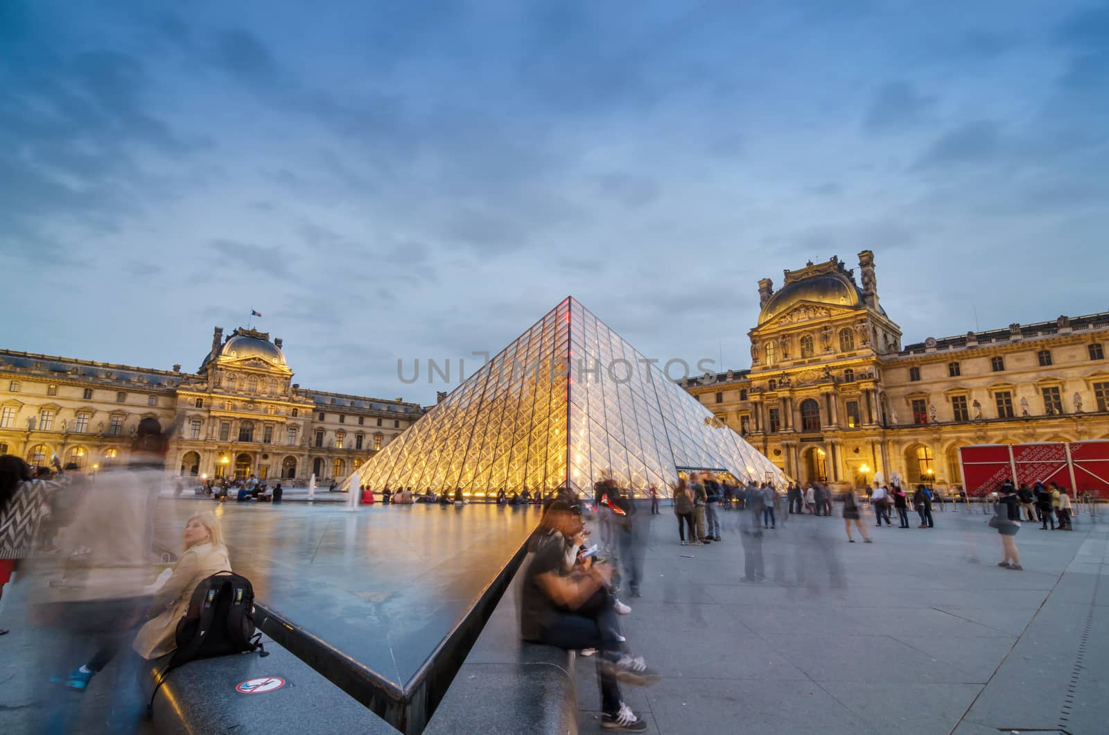 Paris, France - May 14, 2015: Tourists visiting Louvre museum at dusk by siraanamwong