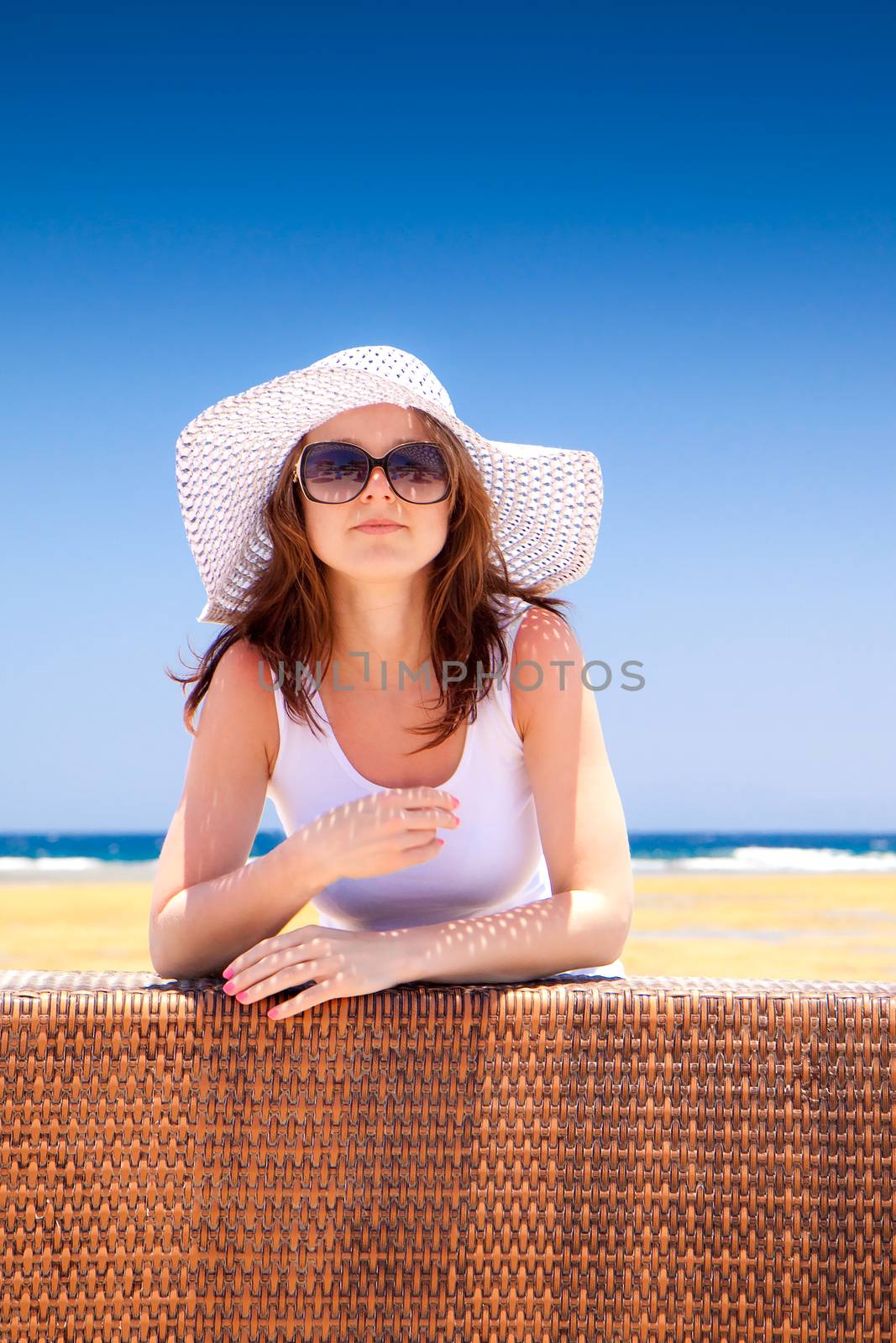 The young beautiful woman in a hat on vacation, on a sunny beach